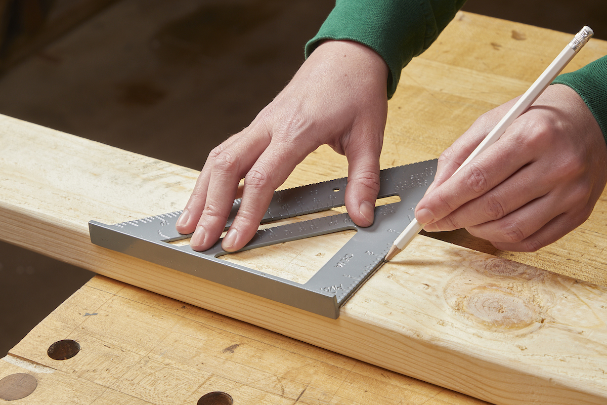Woman measuring a board before making a cross cut with a circular saw.