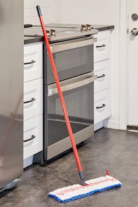 O'Cedar Hardwood Floor N' More Mop leaning against a kitchen cabinet.