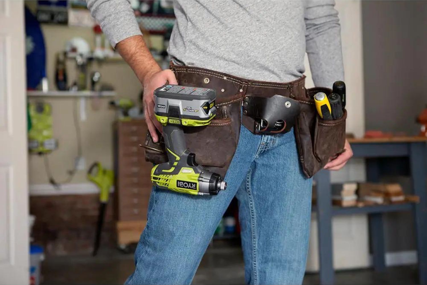 A person wearing a tool belt that has the best Ryobi drill hanging from it.