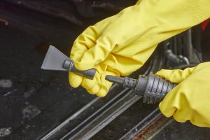 Woman wearing cleaning gloves fits a nozzle on a steam cleaner.
