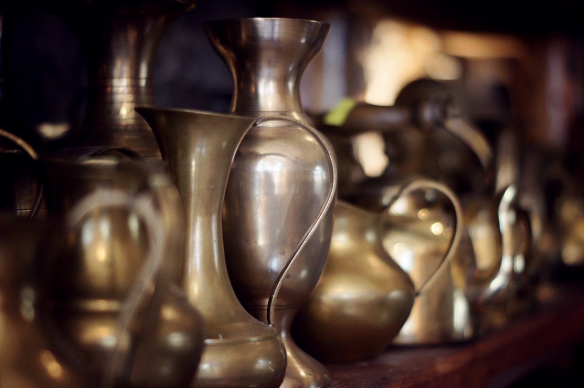 Multiple tarnished brass vases in a row