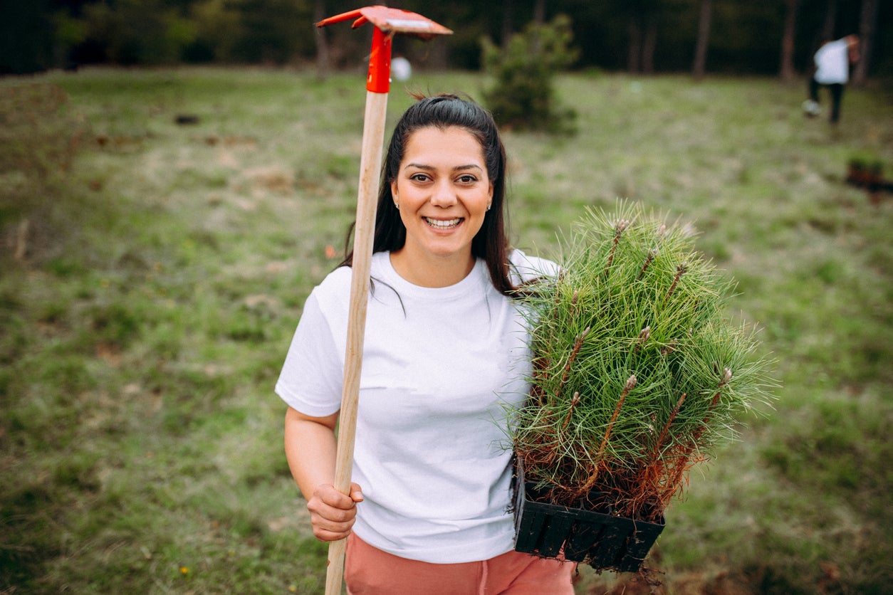 Young woman holding a hoe and tree saplings