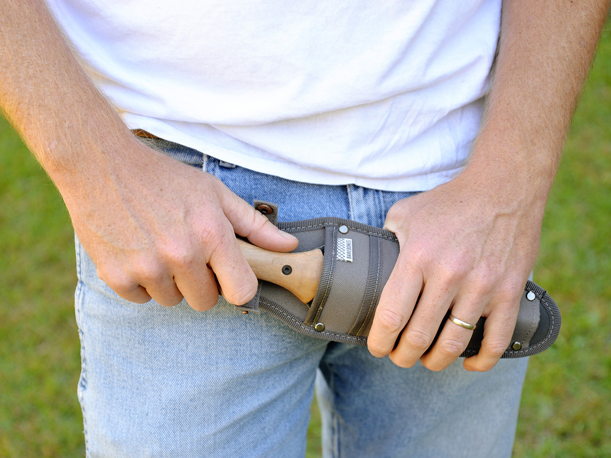 A person pulling the best hori hori knife option out of its sheath.
