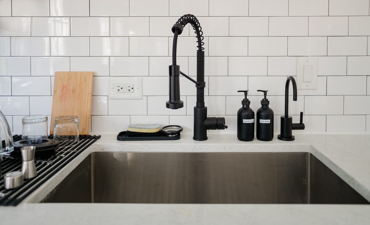 An undermount sink with black fixtures and a white subway tile backsplash.