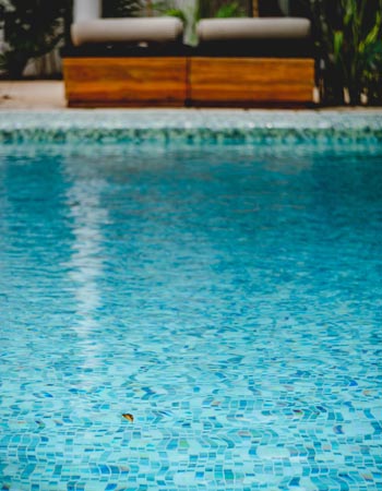 A sparkling blue pool with two lounge chairs along the side of the pool.