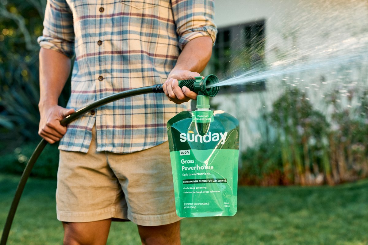 Man spraying Sunday Lawn Care Grass Powerhouse packet to feed the lawn