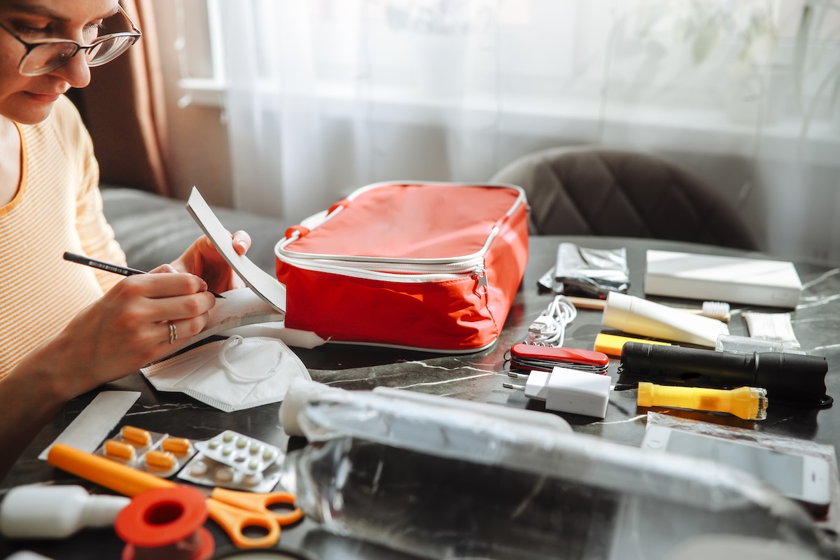 Woman checking contents of emergency first aid kit against a written list.