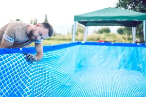 A repairperson applies a new liner to an above-ground pool.