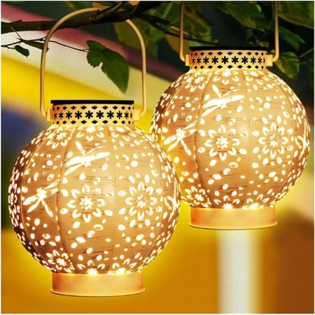  2 Kooper Solar-Powered Integrated LED Outdoor Lanterns on a yellow ground with green leaves