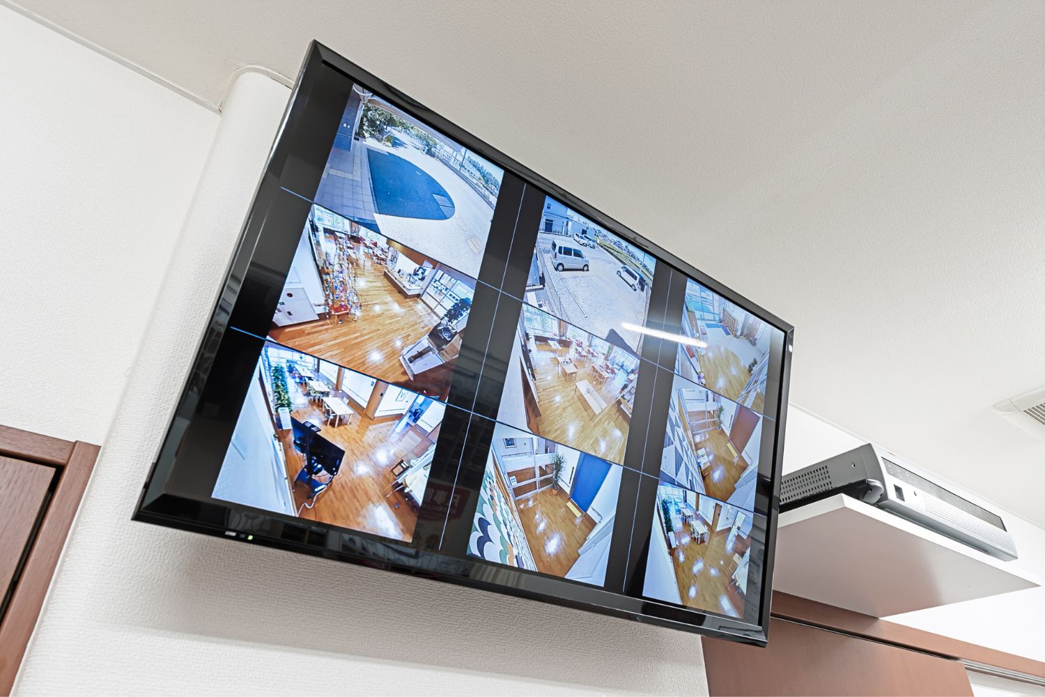 A large-screen TV displays feeds from nine security cameras positioned around a home.