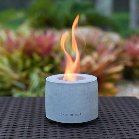  The Colsen Indoor/Outdoor Round Tabletop Fire Pit on an outdoor table with a small flame coming out of it.