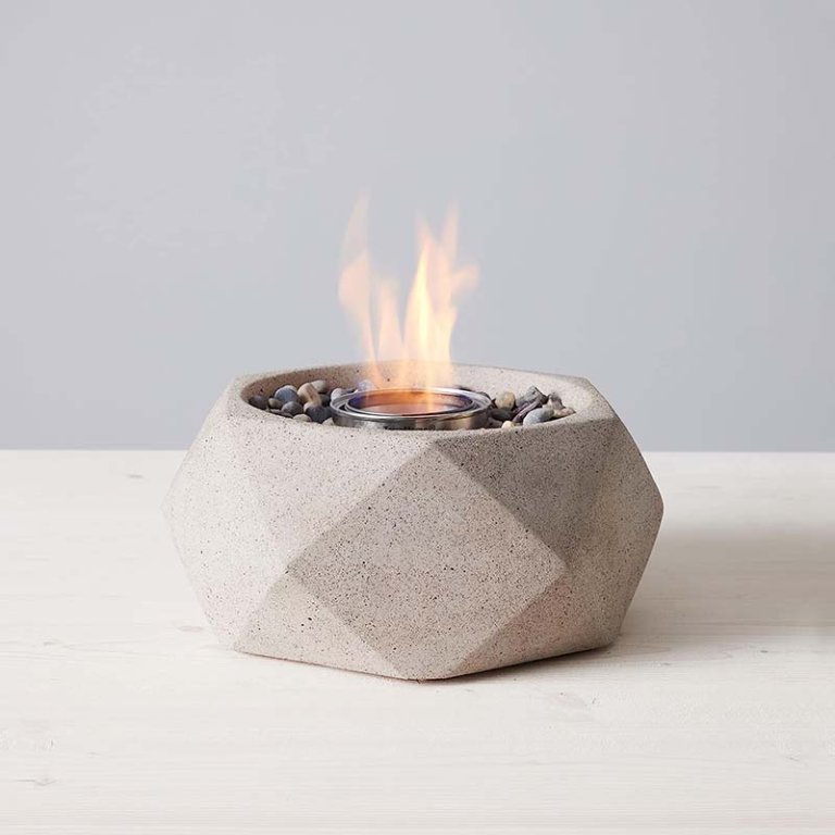  The TerraFlame Geo Tabletop Fire Bowl on a table with a small flame coming from it.