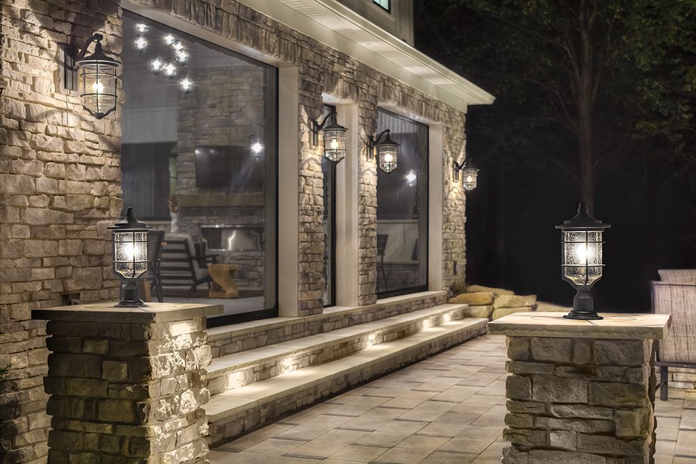 A beautiful bak patio lit by the best outdoor solar lights on the house, stairs, and decorative columns