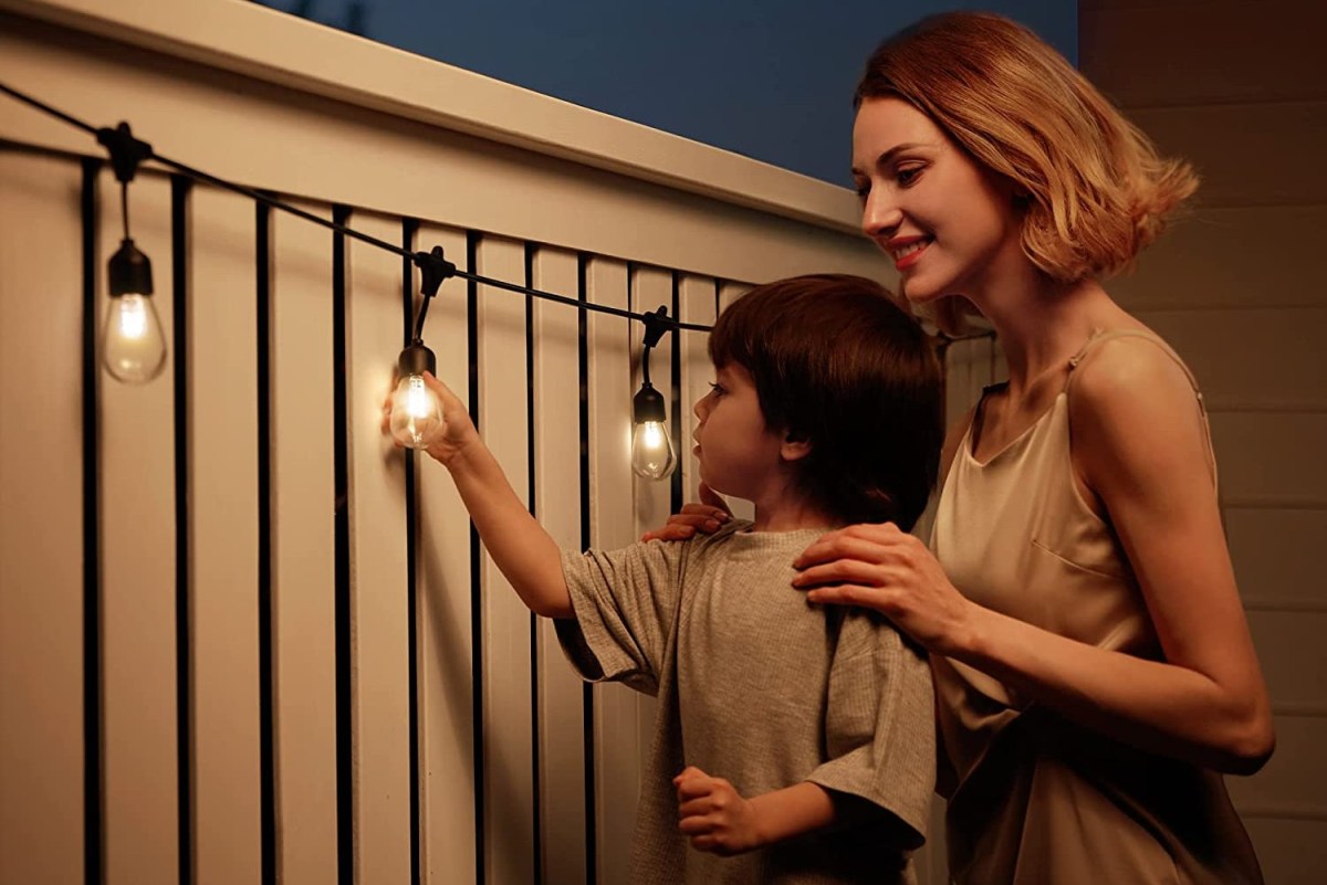 A parent and child looking at the best outdoor solar lights strung on a fence