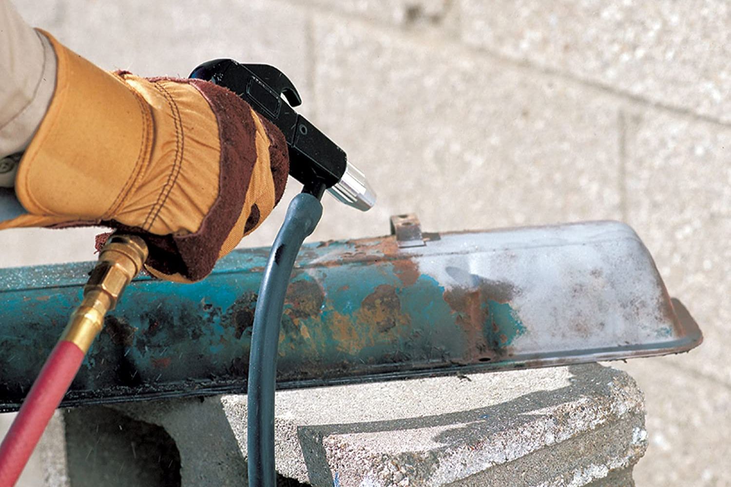 A person using the best sandblaster option to remove rust from metal