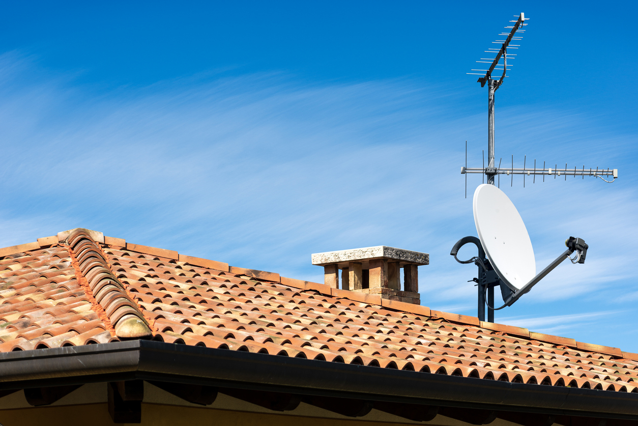A satellite for television propped on a terra cotta roof. 
