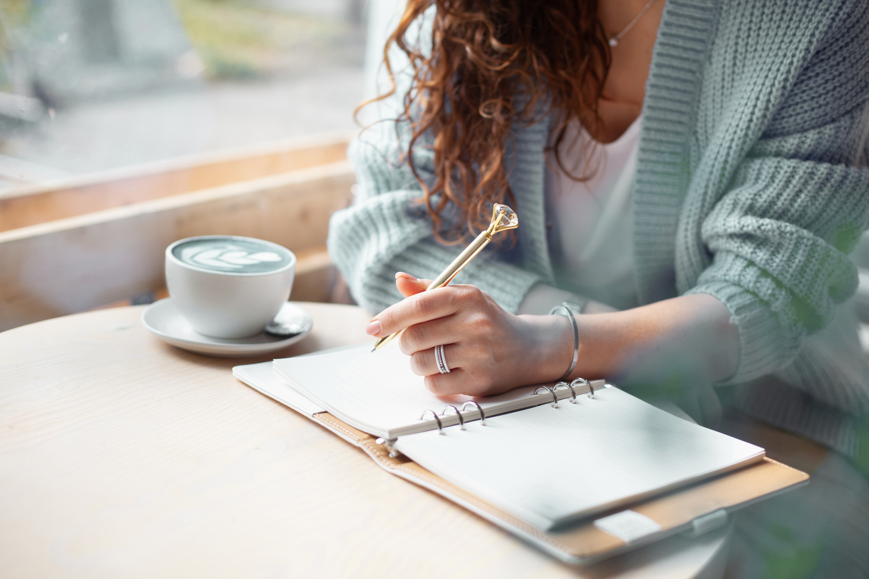 A woman writes in a notebook.
