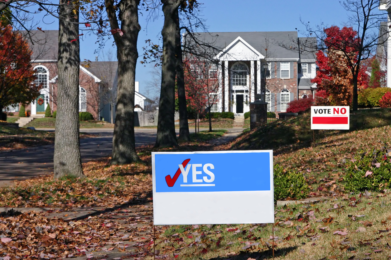 Voting signs in the front yards of homes in a residential neighborhood. 