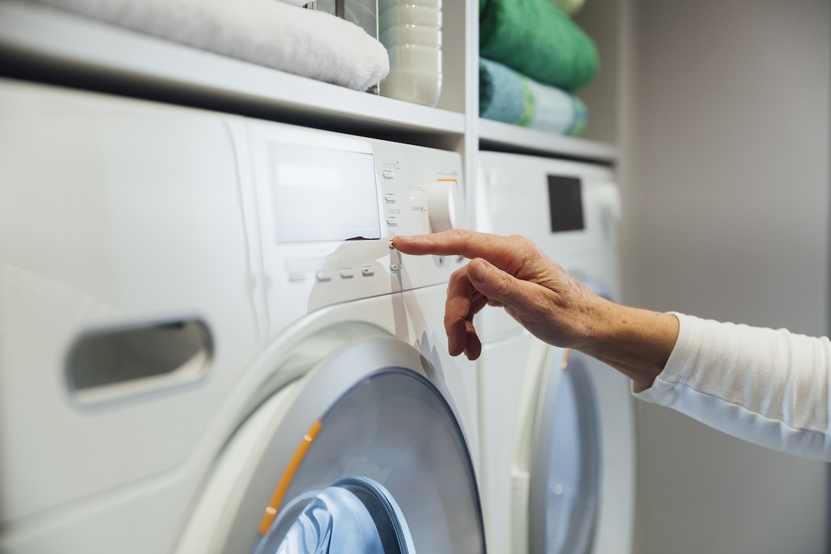 A person selecting a washing machine setting.