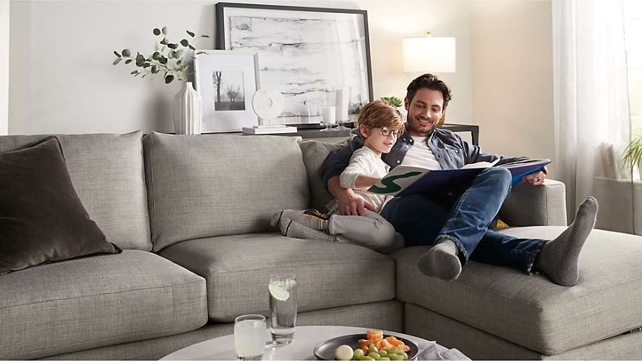 A parent and child snuggled on the best sectional for small spaces option while reading a book