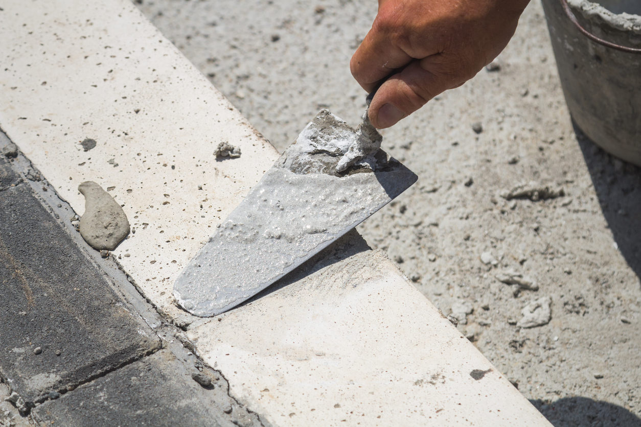Construction worker leveling concrete pavement outdoors.