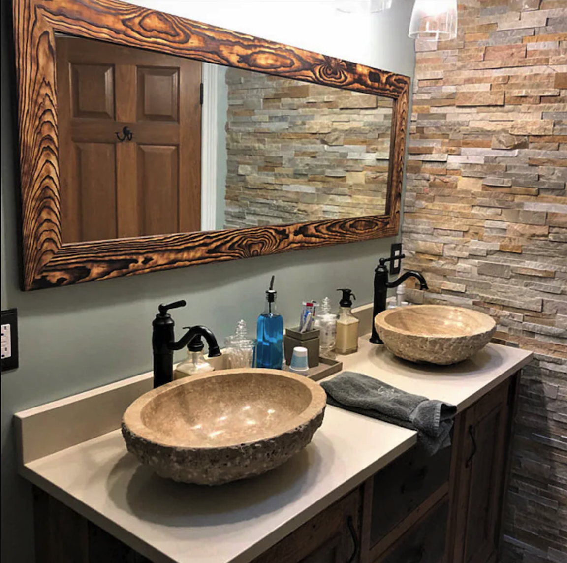 Rustic wood-framed horizontal bathroom mirror over a bathroom vanity.