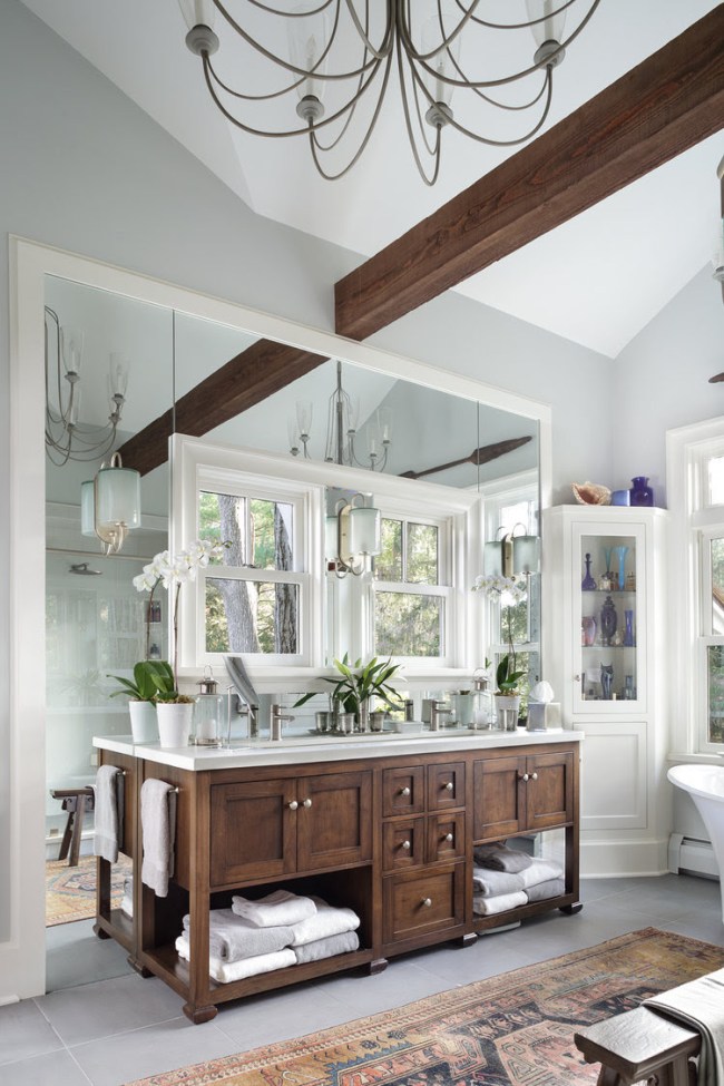 Two bathroom windows over a double vanity sink framed by mirrors in an upscale bathroom