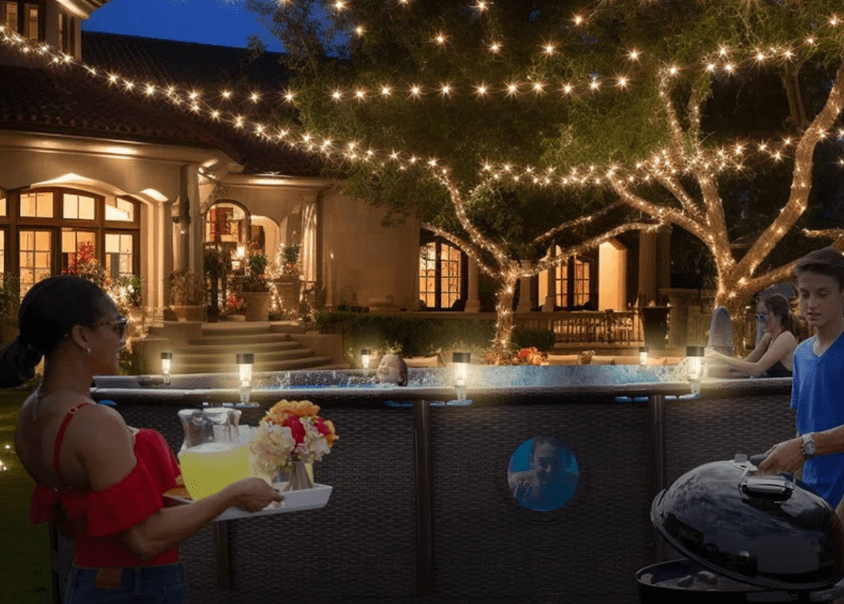 An above-ground pool with lights on it&rsquo;s gutter area and string lights hanging above.