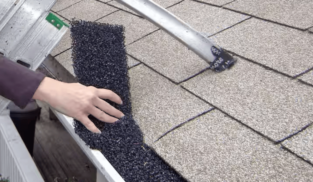 A professional roofer adds foam gutter guards to residential gutters.