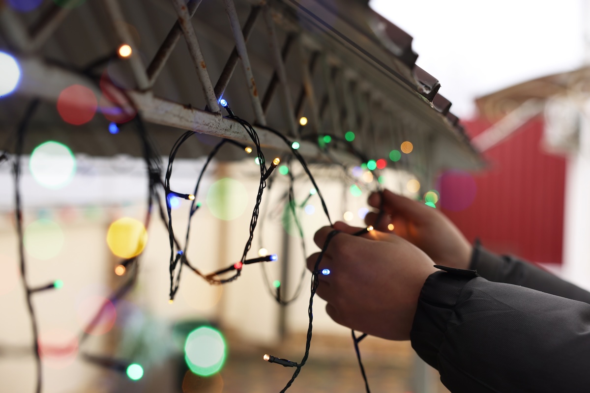 Man decorating house with Christmas lights outdoors, closeup.