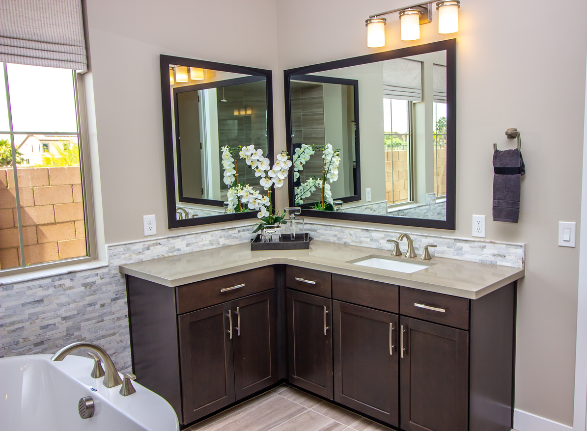 Two bathroom vanity mirrors facing each other over a corner vanity.