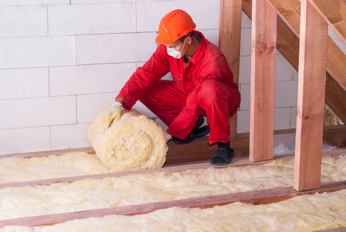 12 Ways to Make an Old Home More Energy Efficient - man unrolling insulation