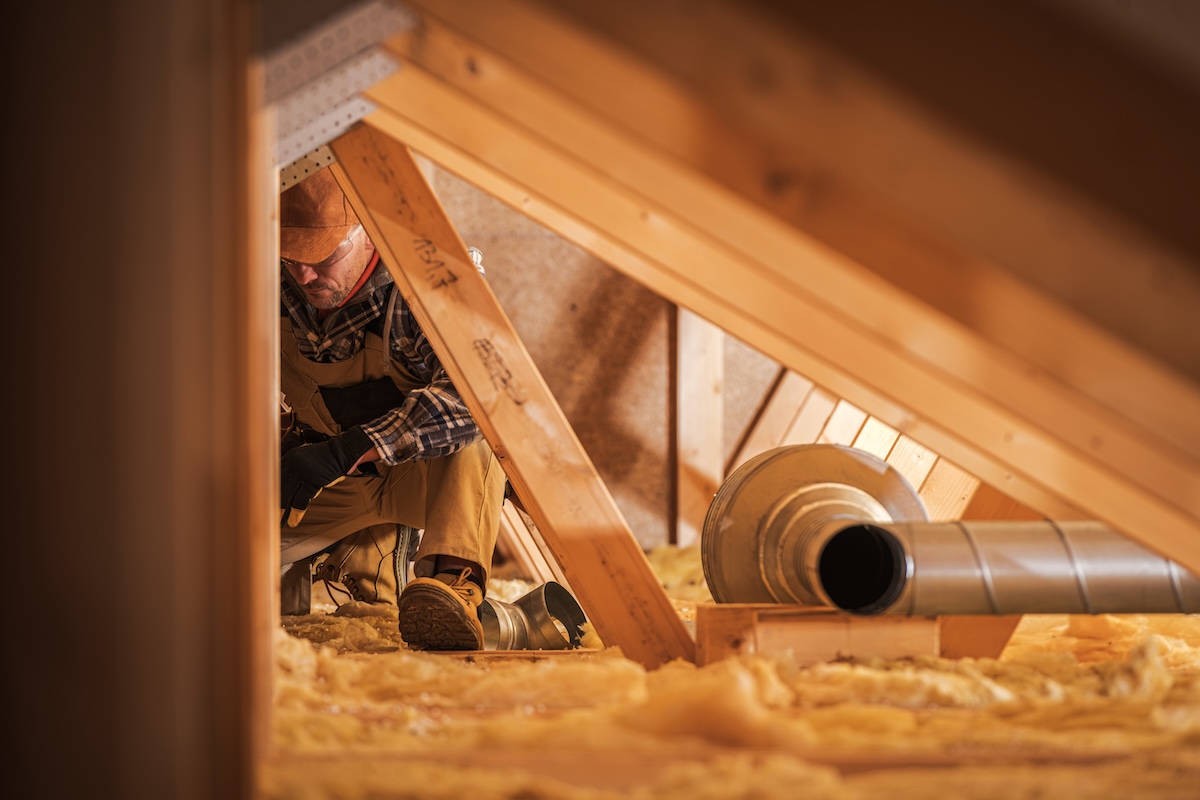 Worker among attic insulation and ventilation.