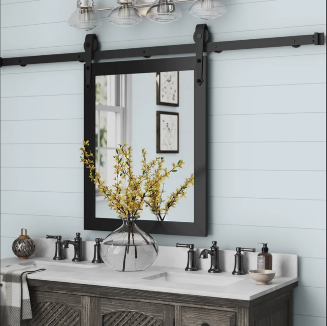 Bathroom mirror on a barn door-inspired track over a double vanity sink
