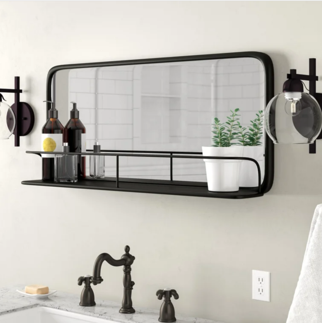 Small black bathroom mirror with a metal shelf built into its frame