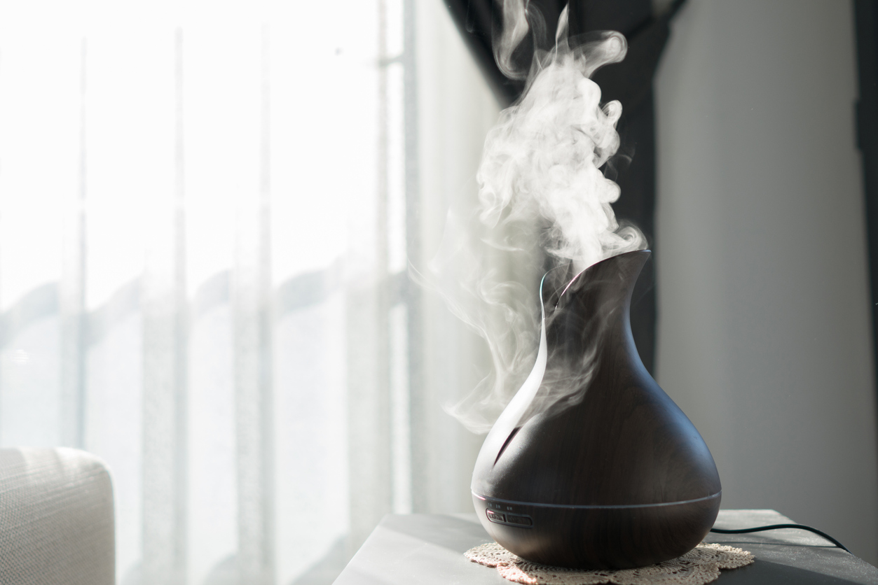 Essential oil diffuser producing thick white vapor on a table