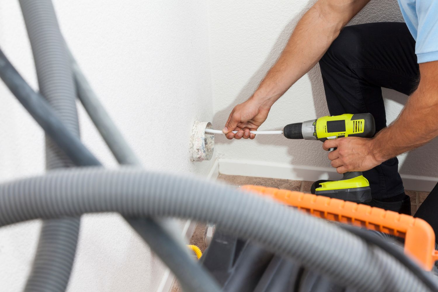 A worker uses a hole in the wall to clean a dryer vent. 