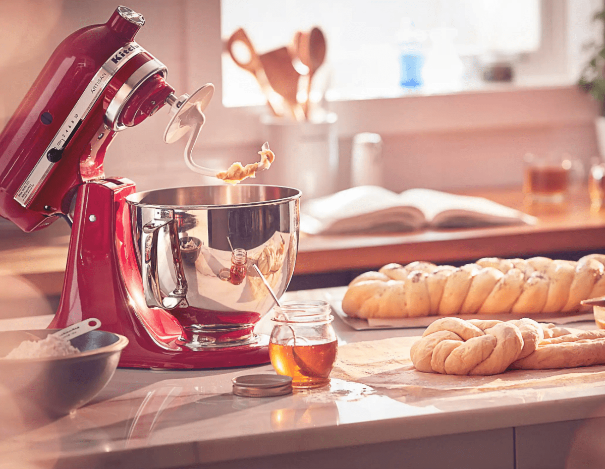 A stand mixer sitting on a counter top with some bread.