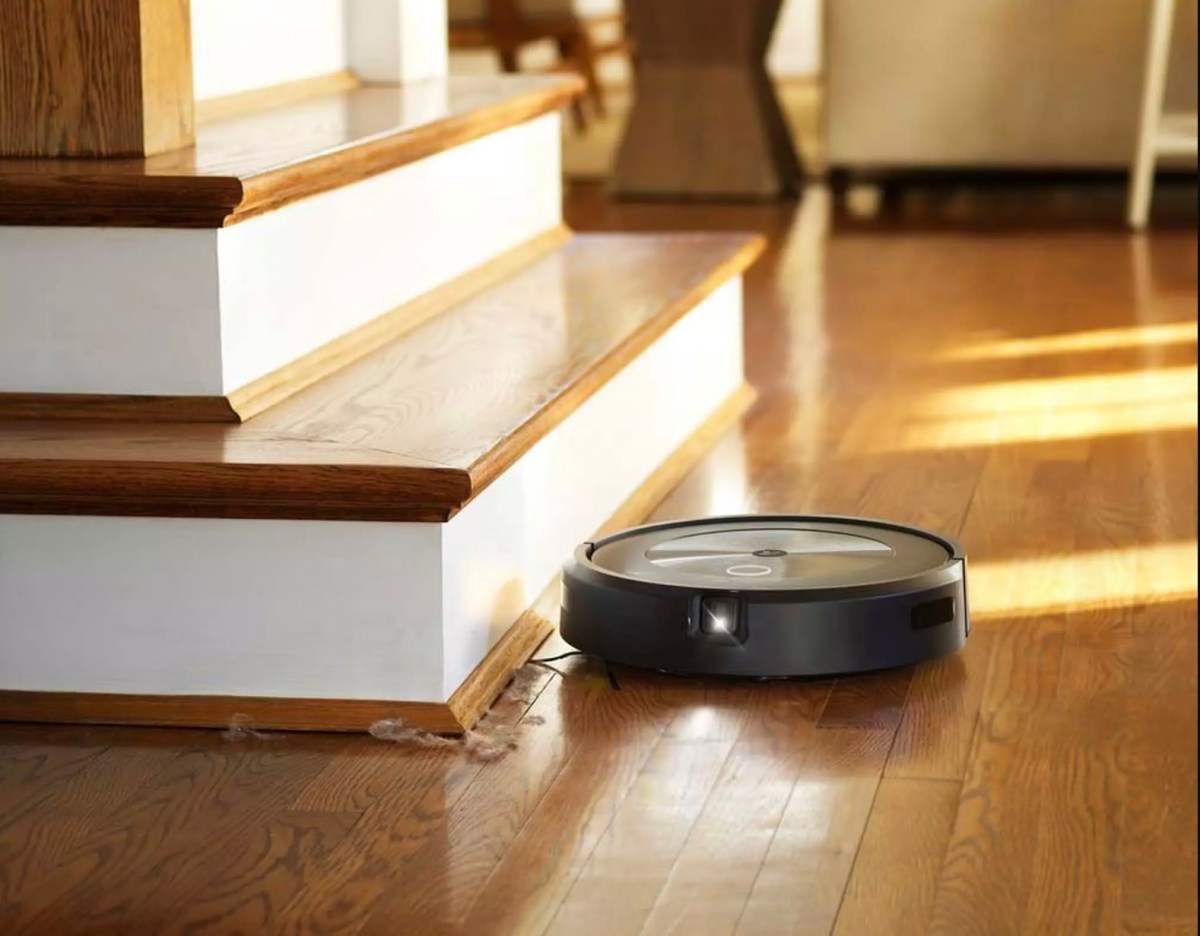 A robotic vacuum sitting at the base of some stairs