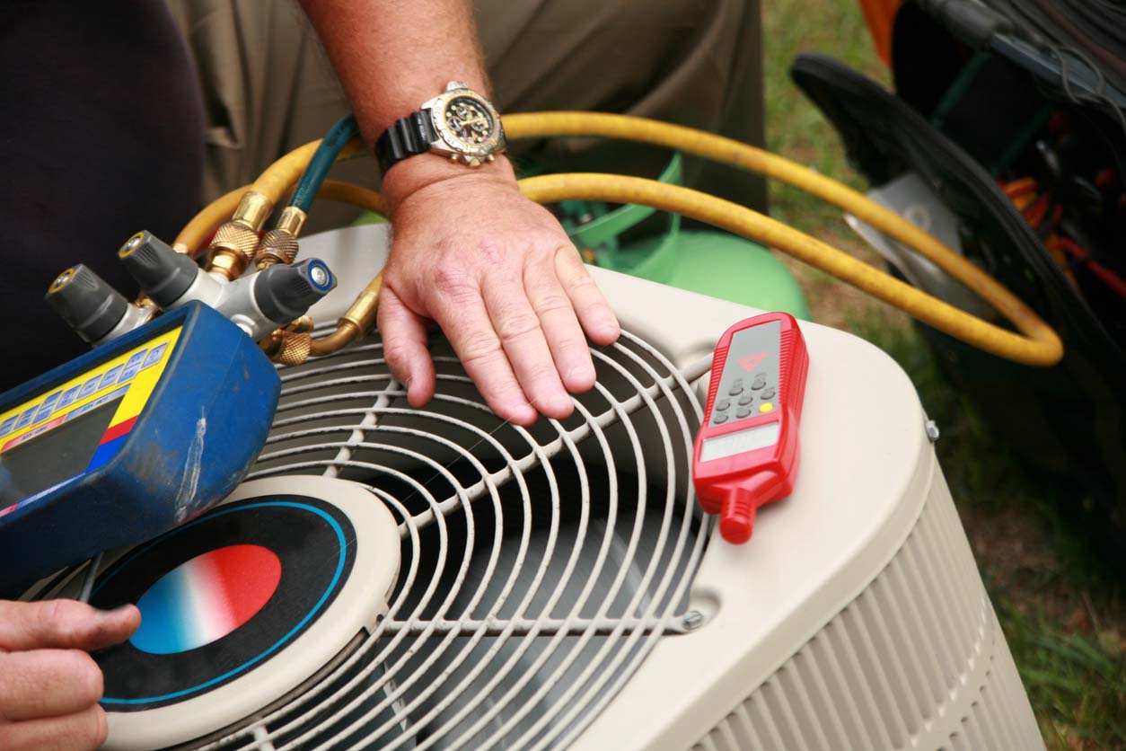 A worker uses tools to assess an HVAC system.