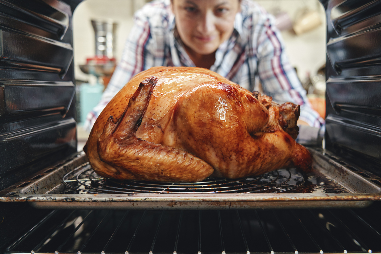 iStock-1280406520 turkey shortage woman taking turkey out of oven
