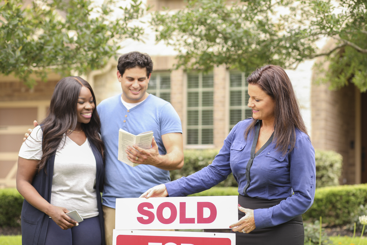 how much does a real estate agent make per sale couple and agent putting up sold sign