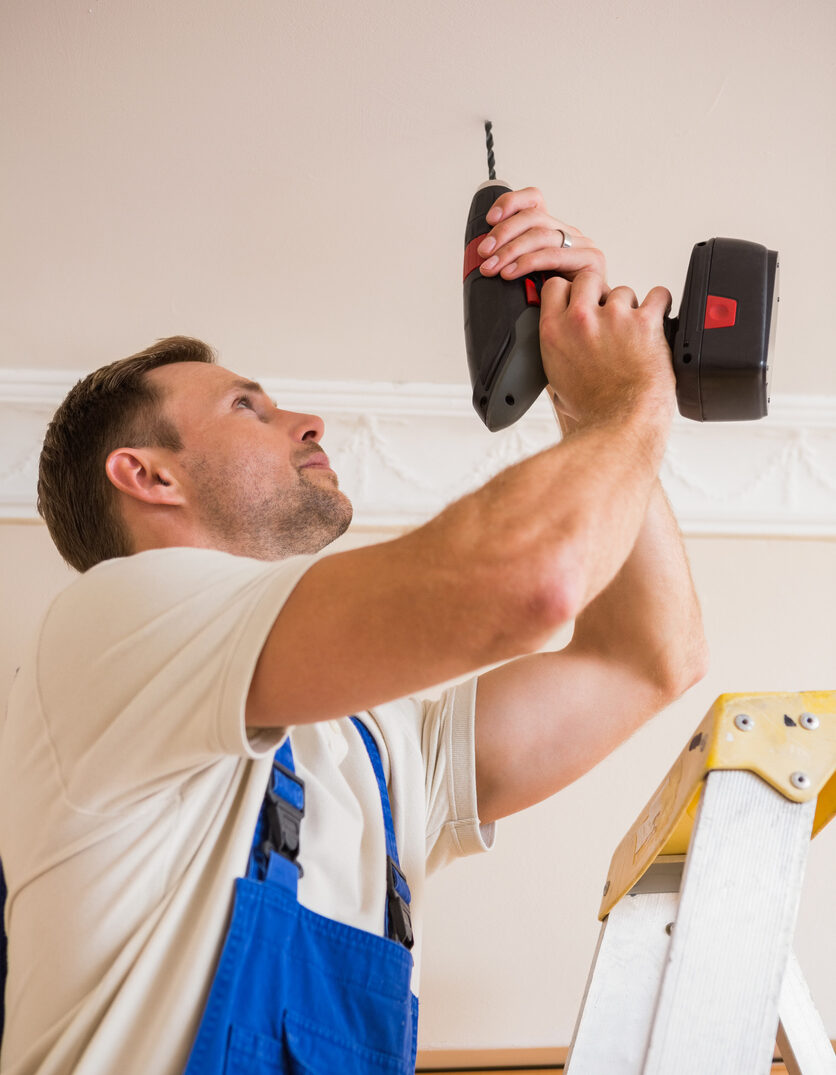 Man drilling a pilot hole in ceiling.