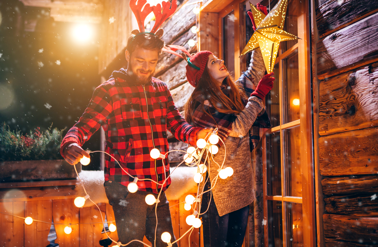 iStock-615632932 must dos December couple hanging holiday lights outside