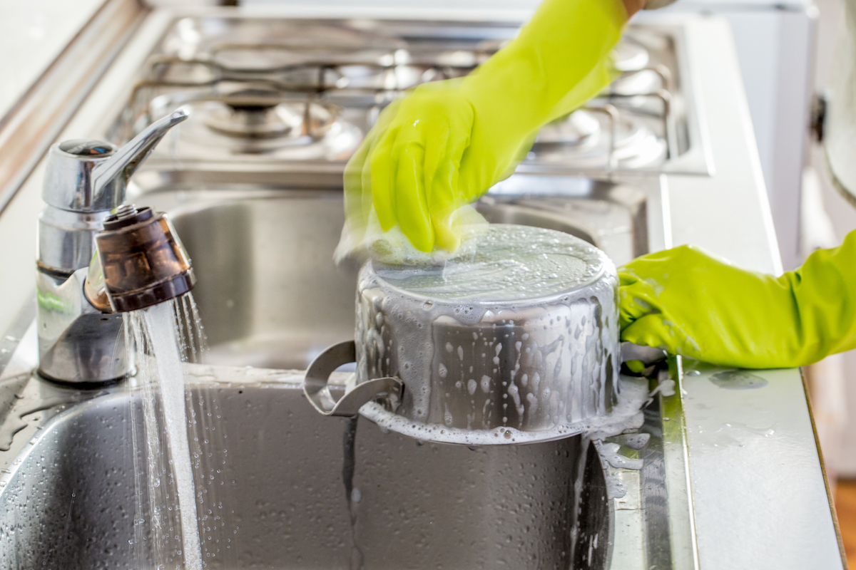 Woman Washing Dishes With Gloves at home.