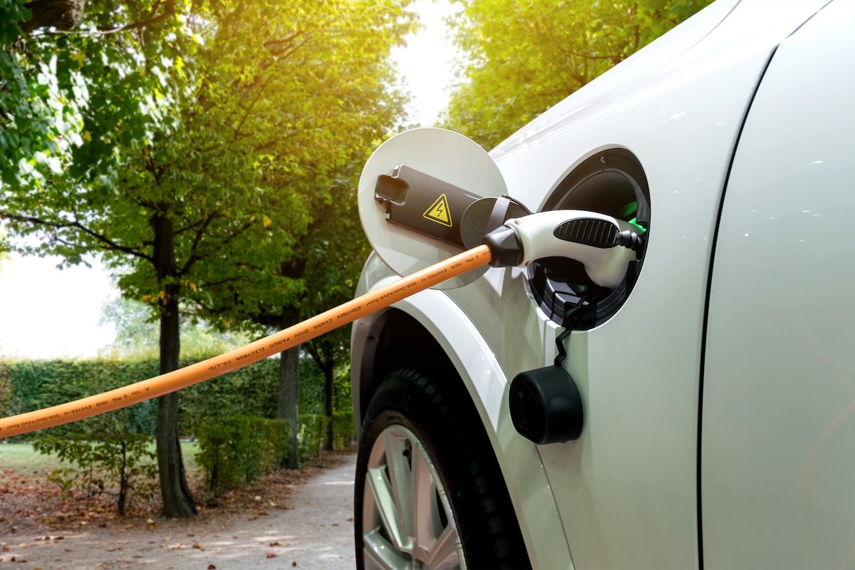 Charging a silver electric car with the power cable supply plugged in.