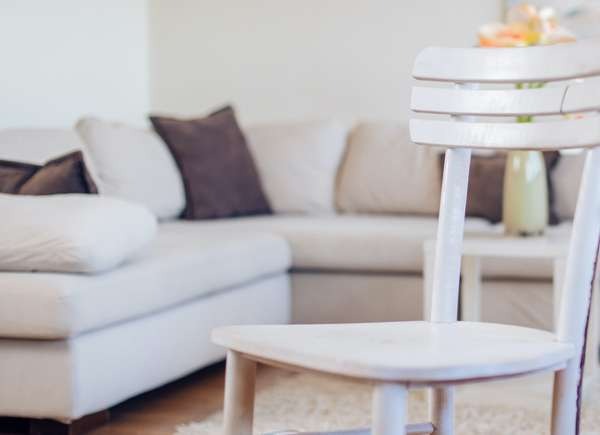 White wooden chair in a family room with a white-grey chaise lounge.