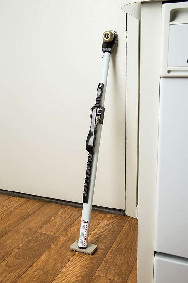 Door jammer leaning up against a white door on a wood floor.