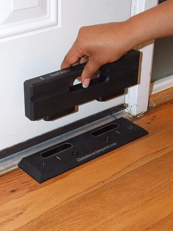 Black floor barricade installed in front of a white door on a wood floor.