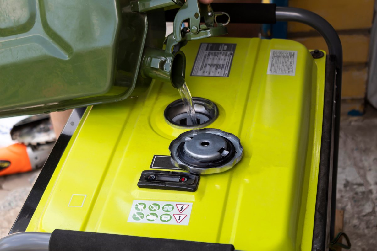 Gasoline is poured into the generator tank from a canister.